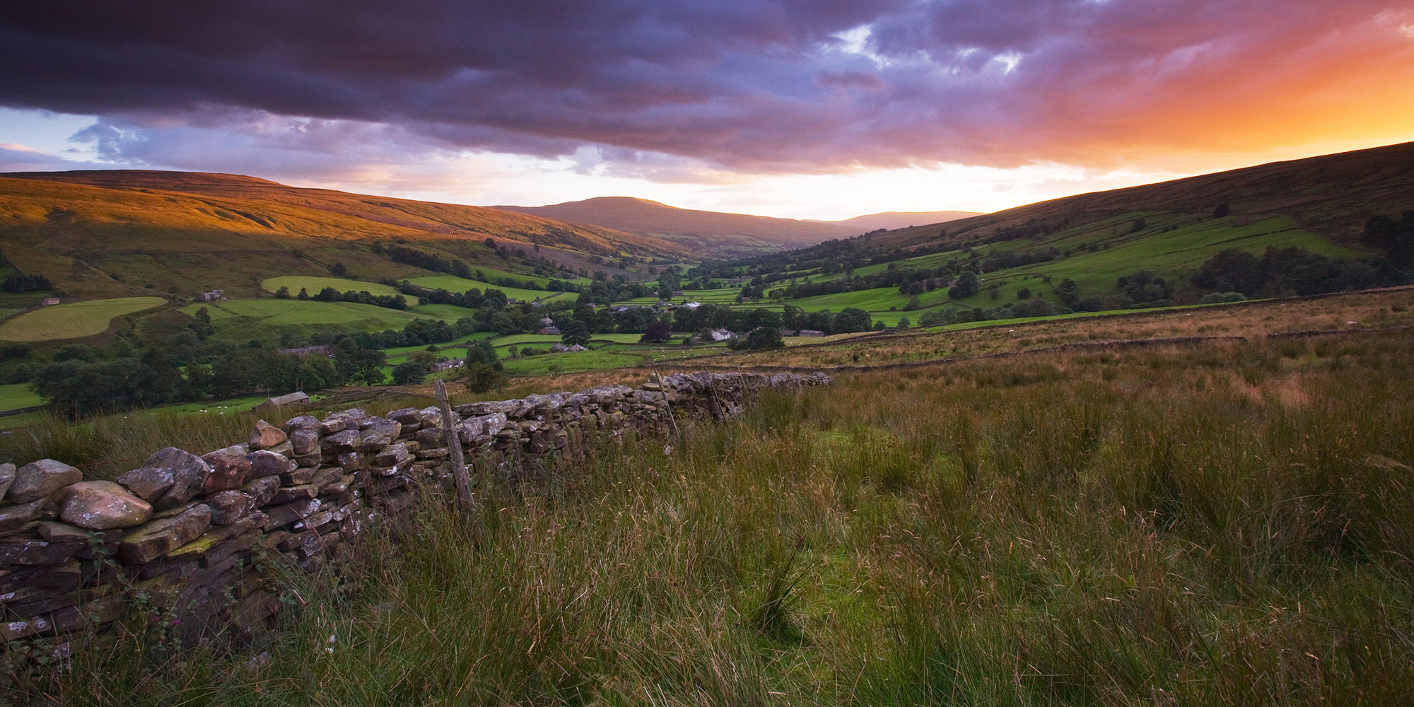 Sunset over hills with traditional dry stone walls in the foreground