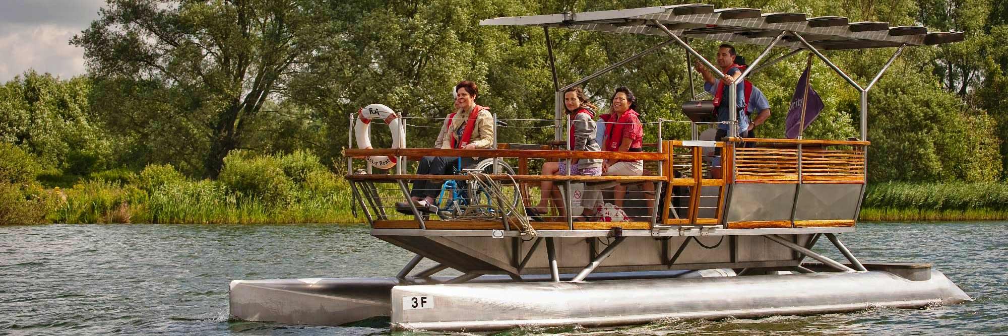 People, including a wheelchair user, on a solar boat on a lake