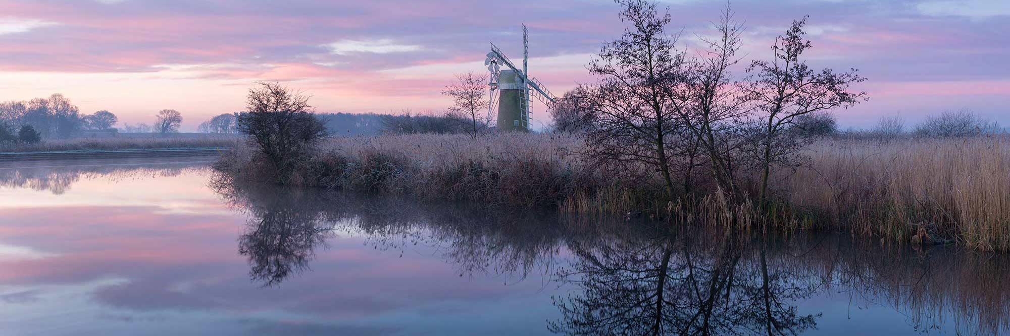 Winter trees and a windmill relected in a lake