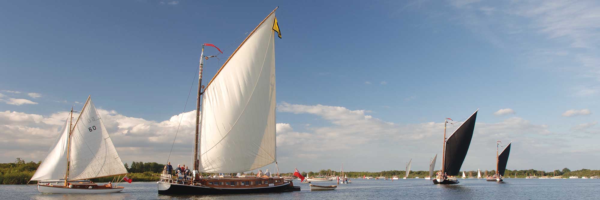 Large sailed wooden boats sailing on the Broads