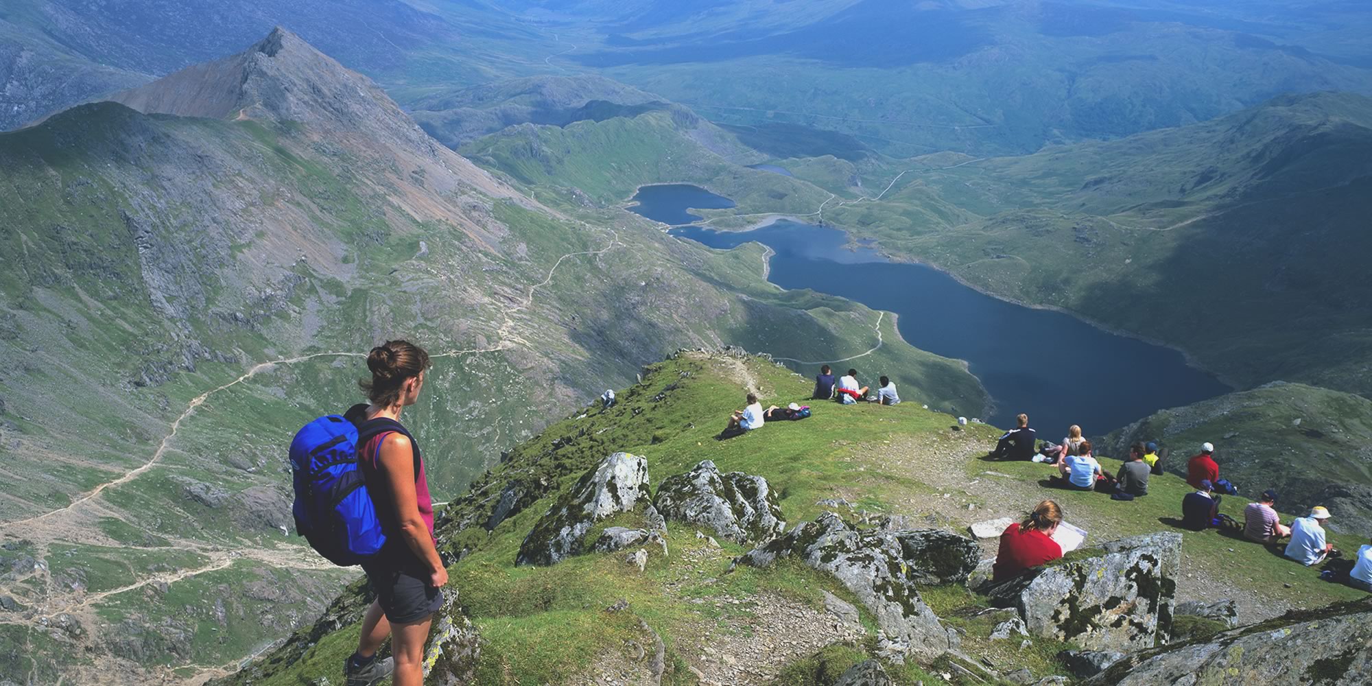 Walkers enjoying a view over tarns and a glacial valley below