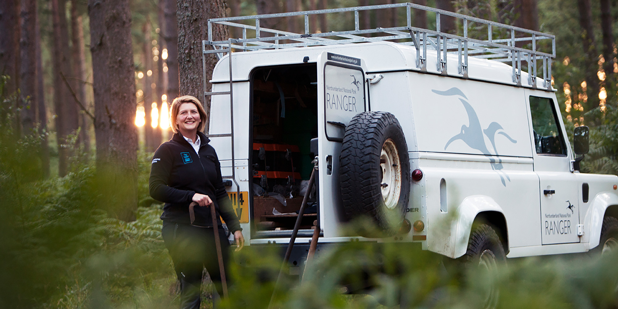 A ranger putting equipment into the back of a land rover van